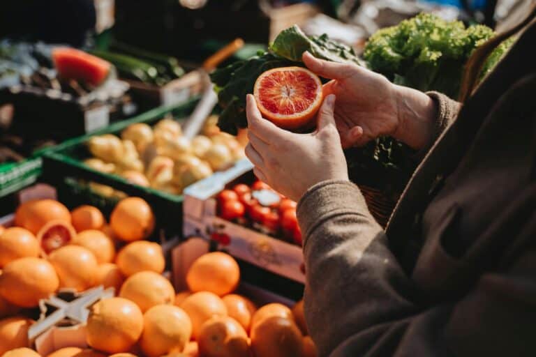 A woman is holding a sliced grapefruit in a local market in the concept of local shops and markets in East London.